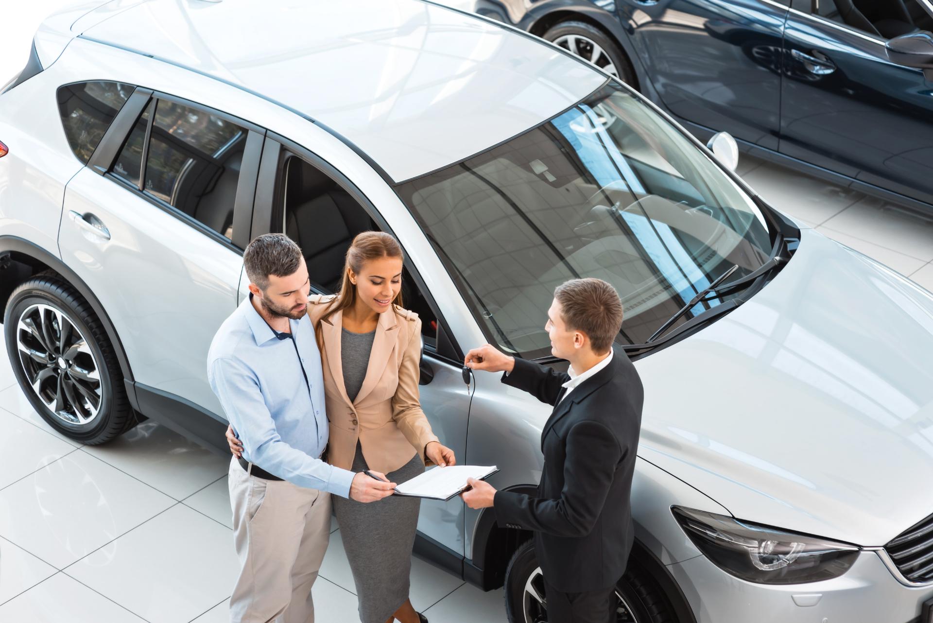 Car dealer handing car keys to couple